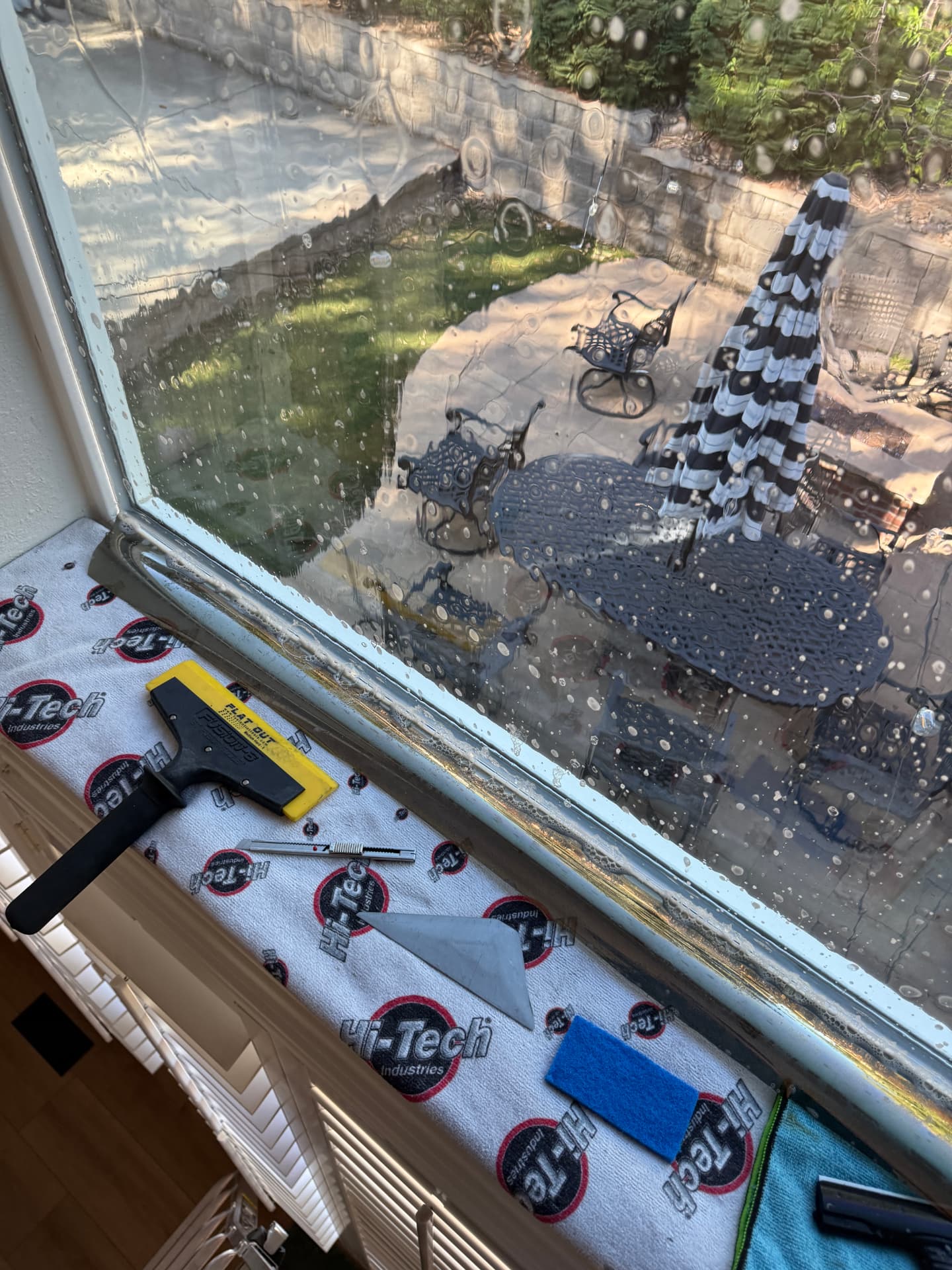 Wet-applied residential window film being squeegeed smooth on a Colorado home window with installation tools staged on the sill